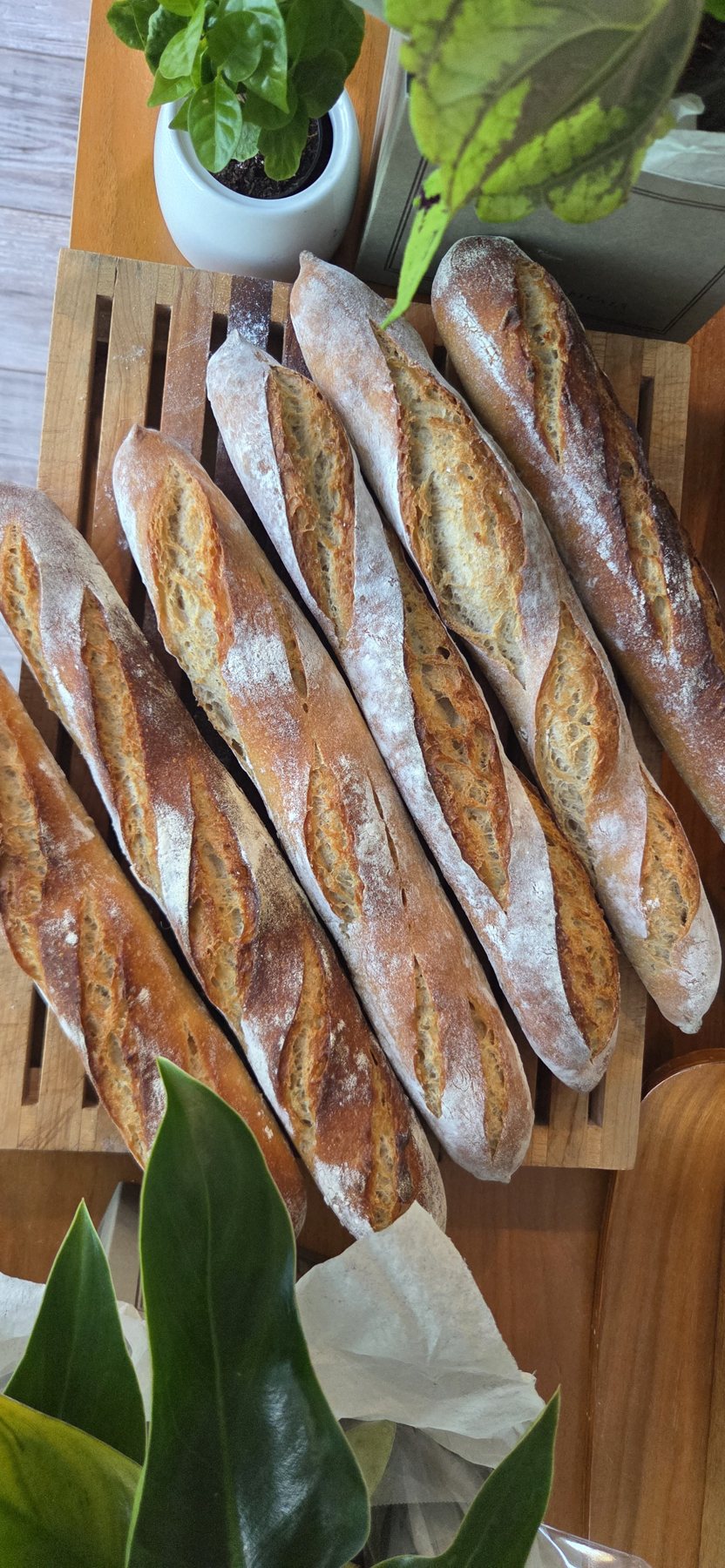 Freshly baked sourdough baguettes on a wooden bread board